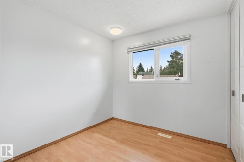 Light-toned wood-finish flooring, white walls, and a window with white blinds - 10007 168 Avenue Nw, Edmonton, AB - Indoor Photo Showing Other Room