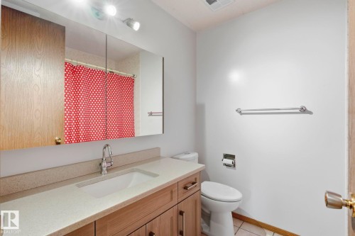 Wood-finish vanity with an integrated sink and light-toned countertop - 10007 168 Avenue Nw, Edmonton, AB - Indoor Photo Showing Bathroom