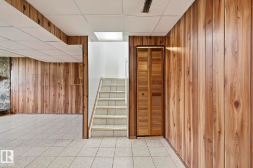 Finished space with tile flooring, wood paneling, drop ceiling, and staircase - 10007 168 Avenue Nw, Edmonton, AB - Indoor Photo Showing Other Room