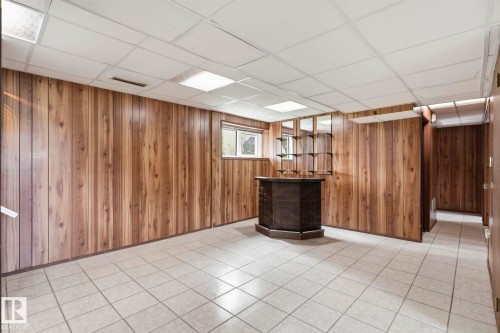 Built-in bar with dark wood finish, tile flooring, wood-paneled walls, drop ceiling with recessed lighting, and a window - 10007 168 Avenue Nw, Edmonton, AB - Indoor