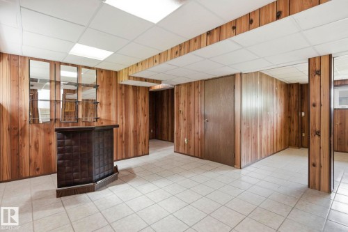 Wood-paneled walls with a built-in bar feature, grid ceiling, and tiled flooring - 10007 168 Avenue Nw, Edmonton, AB - Indoor Photo Showing Other Room