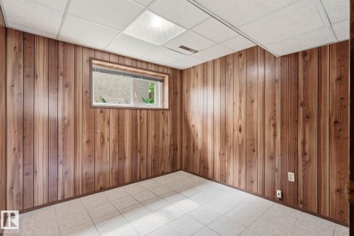 Wood-finish paneling, white grid ceiling, recessed lighting, tile flooring, and a single window - 10007 168 Avenue Nw, Edmonton, AB - Indoor Photo Showing Other Room