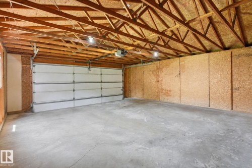 Attached garage featuring a concrete floor, exposed wood ceiling trusses, and a panel-style garage door - 10007 168 Avenue Nw, Edmonton, AB - Indoor Photo Showing Garage