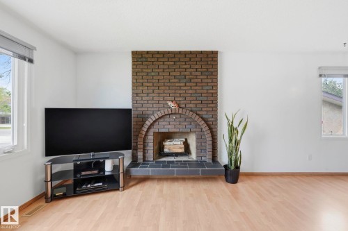 Brick fireplace with an arched hearth, black tile surround, and wood-finish flooring - 10007 168 Avenue Nw, Edmonton, AB - Indoor Photo Showing Living Room With Fireplace