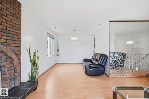 Brick fireplace with arched firebox and slate hearth, light wood-finish flooring, white walls, and decorative glass paneling - 10007 168 Avenue Nw, Edmonton, AB - Indoor