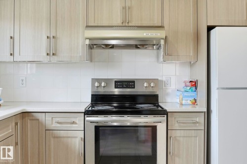 Light wood-finish cabinetry, stainless steel range, white tile backsplash, and light-toned countertops - 10007 168 Avenue Nw, Edmonton, AB - Indoor Photo Showing Kitchen