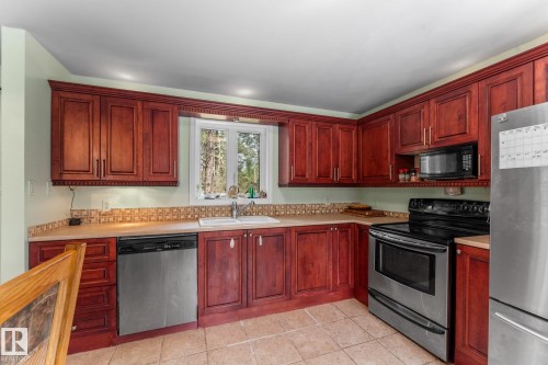 Cherrywood cabinets,  central island,  stainless steel appliances, tiled backsplash, and ceramic tile flooring - 2, 59031 Range Rd 232, Rural Thorhild County, AB - Indoor Photo Showing Kitchen