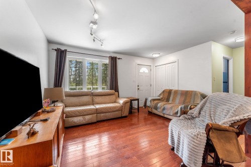 Bright living area featuring wood-finish flooring, a window offering natural light, and a prominent entry door - 2, 59031 Range Rd 232, Rural Thorhild County, AB - Indoor Photo Showing Living Room