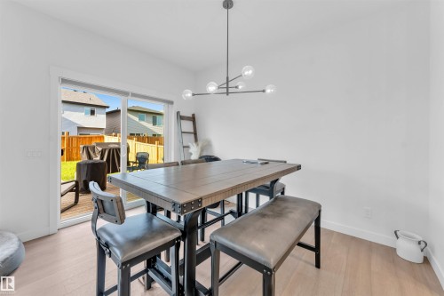 Light-toned wood-finish flooring complements the crisp white walls - 3236 Chernowski Way Sw, Edmonton, AB - Indoor Photo Showing Dining Room