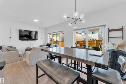 Hardwood-style flooring throughout, modern ceiling light fixture, recessed ceiling light, white walls, and sliding glass patio doors - 3236 Chernowski Way Sw, Edmonton, AB - Indoor Photo Showing Dining Room