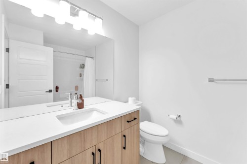 Vanity with wood-finish cabinetry, white countertop, and integrated sink - 3236 Chernowski Way Sw, Edmonton, AB - Indoor Photo Showing Bathroom