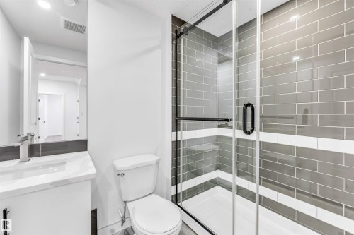 Walk-in shower with clear glass enclosure, gray subway tile, and a white accent band - 3236 Chernowski Way Sw, Edmonton, AB - Indoor Photo Showing Bathroom
