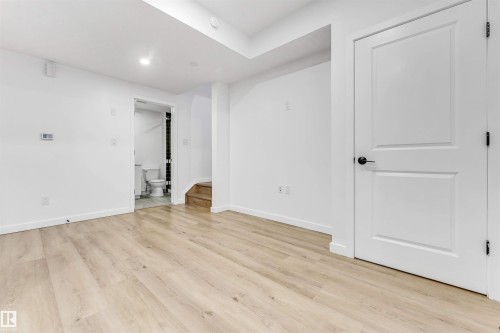 Basement: Light wood-finish flooring, recessed lighting, white walls, and a white two-panel interior door with a matte black knob - 3236 Chernowski Way Sw, Edmonton, AB - Indoor Photo Showing Other Room