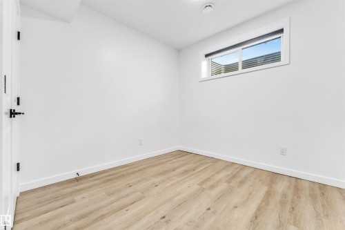 Recessed window with exterior enclosure, wood-finish flooring, white walls, and a white paneled door with black hardware - 3236 Chernowski Way Sw, Edmonton, AB - Indoor Photo Showing Other Room