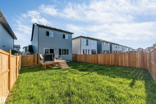 Expansive backyard featuring a manicured lawn, full wood fencing, and a raised wooden deck with stairs - 3236 Chernowski Way Sw, Edmonton, AB - Outdoor With Exterior