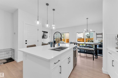 Kitchen island with undermount sink, pendant lighting, and white cabinetry - 3236 Chernowski Way Sw, Edmonton, AB - Indoor Photo Showing Kitchen With Double Sink With Upgraded Kitchen