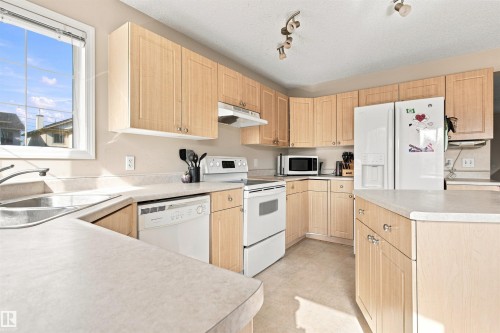 Kitchen featuring light wood-finish cabinetry, light-toned countertops, and a double basin sink - 204 84 Street Sw, Edmonton, AB - Indoor Photo Showing Kitchen With Double Sink