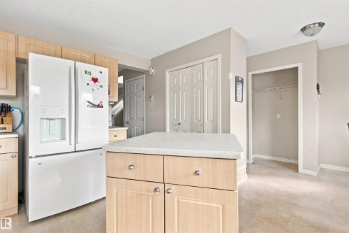 Kitchen featuring a central island with storage, light wood-finish cabinetry, and neutral-toned flooring - 204 84 Street Sw, Edmonton, AB - Indoor Photo Showing Kitchen