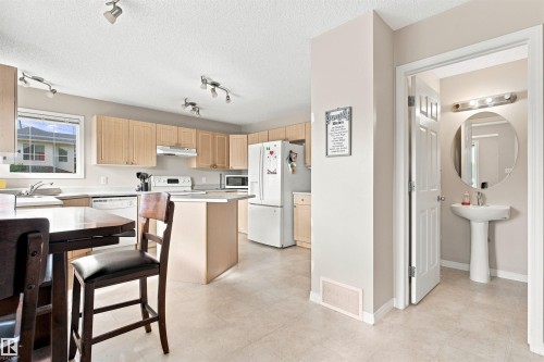 Kitchen featuring light wood-finish cabinetry, white countertops, a central island, and white appliances - 204 84 Street Sw, Edmonton, AB - Indoor Photo Showing Kitchen