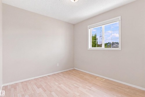 Neutral-toned walls complement wood-finish flooring - 204 84 Street Sw, Edmonton, AB - Indoor Photo Showing Other Room