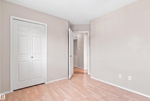 Wood-finish flooring with white trim and a neutral paint palette - 204 84 Street Sw, Edmonton, AB - Indoor Photo Showing Other Room