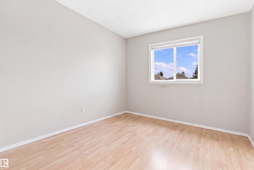 Light wood-finish flooring, white trim, and a window with a white frame - 204 84 Street Sw, Edmonton, AB - Indoor Photo Showing Other Room