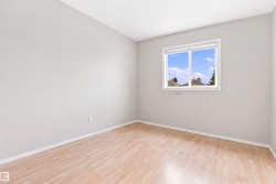 Light wood-finish flooring, white trim, and a window with a white frame - 