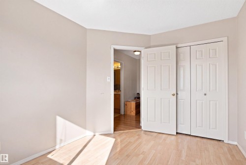 Light-toned wood-finish flooring, neutral wall paint, and white bi-fold closet doors - 204 84 Street Sw, Edmonton, AB - Indoor
