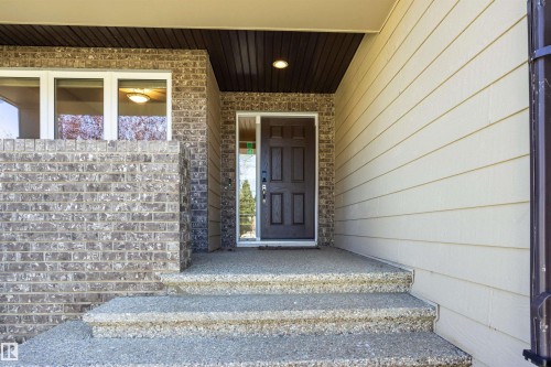 Brick and siding exterior with a paneled entry door - 2043 Cameron Ravine Way Nw, Edmonton, AB - Outdoor With Exterior