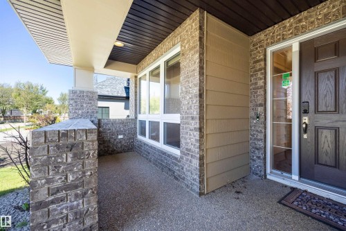 Covered porch with exposed aggregate concrete flooring, brick columns, and a rich wood-paneled ceiling - 2043 Cameron Ravine Way Nw, Edmonton, AB - Outdoor With Exterior