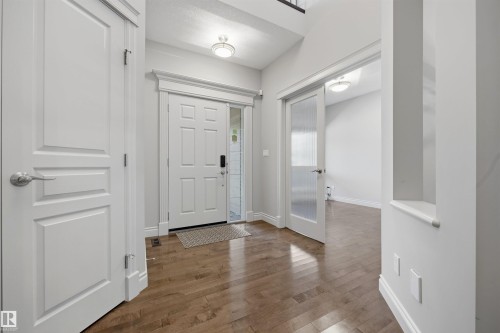 Wood-finish flooring, white paneled doors, recessed wall niche, and frosted glass interior door - 2043 Cameron Ravine Way Nw, Edmonton, AB - Indoor Photo Showing Other Room