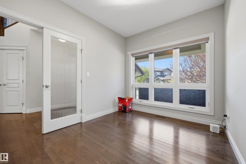 Hardwood-finish flooring, white trim, and a large multi-pane window - 2043 Cameron Ravine Way Nw, Edmonton, AB - Indoor Photo Showing Other Room