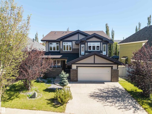 Exterior featuring a two-car garage, concrete driveway, stone accents, and a gabled roofline - 2043 Cameron Ravine Way Nw, Edmonton, AB - Outdoor With Facade