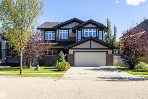 Contemporary facade with a stone and siding exterior, multiple window configurations, an attached garage, a paved driveway, and manicured front landscaping - 2043 Cameron Ravine Way Nw, Edmonton, AB - Outdoor With Facade