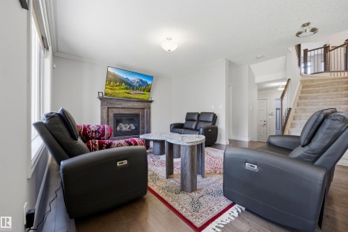 Hardwood-style flooring throughout, featuring a fireplace with a stone surround and mantel - 2043 Cameron Ravine Way Nw, Edmonton, AB - Indoor Photo Showing Living Room With Fireplace