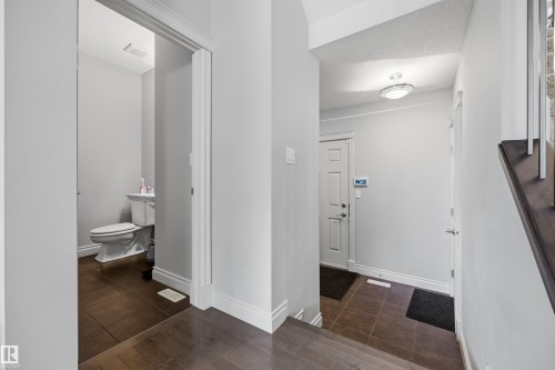 Powder room with a pedestal sink, white toilet, and dark tile flooring - 2043 Cameron Ravine Way Nw, Edmonton, AB - Indoor Photo Showing Other Room