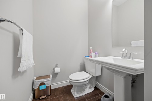 Pedestal sink with chrome fixtures, an overhead wall mirror, and brown-toned tile flooring - 2043 Cameron Ravine Way Nw, Edmonton, AB - Indoor Photo Showing Bathroom