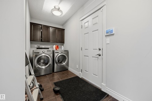 Laundry area featuring dark wood-finish cabinetry, tile flooring, and a flush-mount ceiling light - 2043 Cameron Ravine Way Nw, Edmonton, AB - Indoor Photo Showing Laundry Room