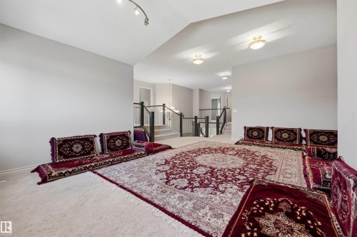 Carpeted flooring extending through the space, light gray wall finishes, and a multi-level layout featuring a prominent staircase with dark wood-finish railings - 2043 Cameron Ravine Way Nw, Edmonton, AB - Indoor