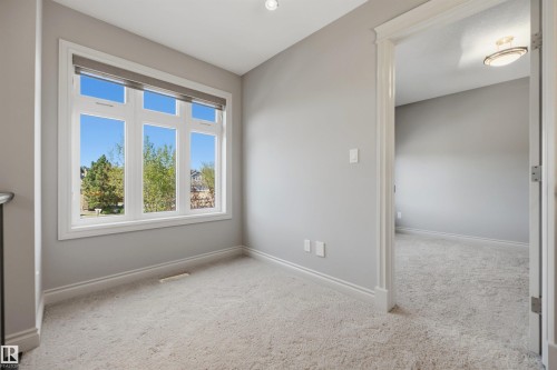 Bright interior featuring light grey walls, white trim, and light-colored carpeting - 2043 Cameron Ravine Way Nw, Edmonton, AB - Indoor Photo Showing Other Room