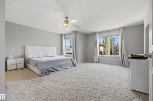 Spacious room featuring light-colored carpeting, two large windows, a ceiling fan, and light gray walls - 2043 Cameron Ravine Way Nw, Edmonton, AB - Indoor Photo Showing Bedroom