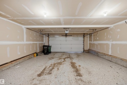 Garage space with an epoxy-coated concrete floor, an overhead door, and exposed drywall - 2043 Cameron Ravine Way Nw, Edmonton, AB - Indoor Photo Showing Garage