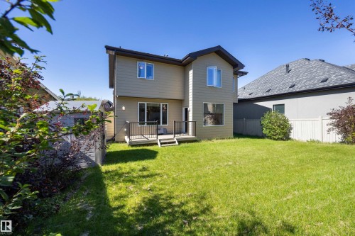 Expansive backyard with a manicured lawn, a raised deck featuring black railings, and a two-story exterior with light-colored siding - 2043 Cameron Ravine Way Nw, Edmonton, AB - Outdoor