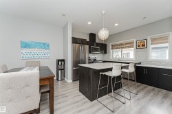 Modern kitchen featuring dark wood-finish cabinetry, stainless steel appliances, and a central island with a light-toned countertop - 