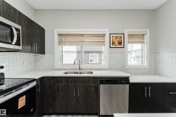 Modern kitchen featuring dark wood-finish cabinetry, white countertops, and a full tile backsplash - 