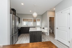 Modern kitchen featuring dark wood-finish cabinetry, stainless steel appliances, a center island with countertop seating, recessed lighting, and wood-finish flooring - 