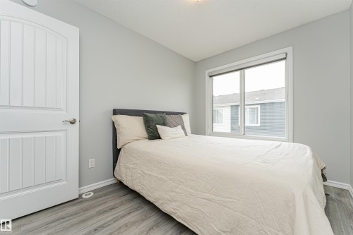 Spacious room featuring light grey walls, wood-finish flooring, and a large window - #61 215 Saddleback Rd Nw, Edmonton, AB - Indoor Photo Showing Bedroom