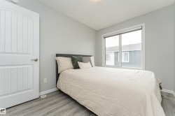 Spacious room featuring light grey walls, wood-finish flooring, and a large window - 