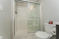 Enclosed shower with sliding glass doors, a handheld showerhead, and light-toned tile surround - 