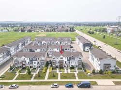 Modern townhome featuring a tri-color facade, private front yard with mature landscaping, and a fenced patio space - 